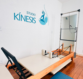 Homem praticando alongamento de pernas em equipamento de Pilates em estúdio iluminado